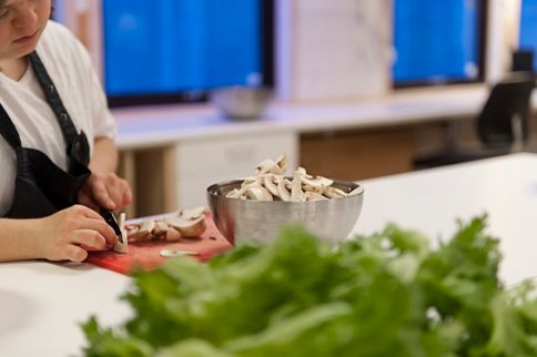 Person på kjøkken kutter sopp på rød fjøl
